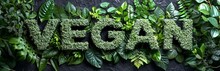 The Inscription "VEGAN" Made Of Fresh Green Leaves On A Dark Background. Concept: Visual Content For Blogs And Stores Specializing In Organic Products
