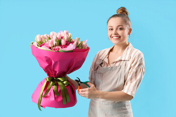 Wall Mural - Beautiful young woman with bouquet of flowers and pruner on blue background