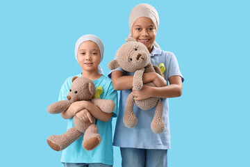 cute little children after chemotherapy with yellow ribbons and teddy bears on blue background. chil