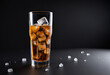 Refreshing soda with ice in glass on dark background with space for text. Water droplet on glass surface.
