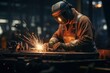 welder wearing protective gear welding metal in factory
