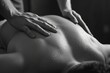 A black and white photo showing a man getting a back massage. Suitable for health and wellness themes