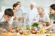 © JackF - Smiling enthusiastic young guy participating group culinary class, engrossed in cooking process mirroring chef instructor steps..