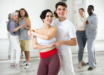 Wall Mural - Caucasian man and young woman learning paired latin dances