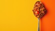 A spoonful of rich, savory chili on a vibrant yellow and orange background