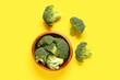 Leinwandbild Motiv Wooden bowl with fresh broccoli cabbages on yellow background