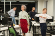 © Михаил Решетников - Four office workers warm up during a break. Employees do fitness exercises at the workplace.