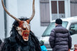 Krampus demon on blurred street background.Carnival processions in Germany. Carnival costumes and characters.Winter costume processions on the streets of Europe.Demon face of Krampus monster.