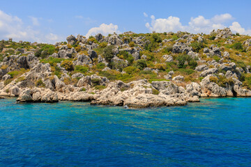 Wall Mural - View of the rocky shore from the sea. Mediterranean Sea in Turkey. Popular tourist places. Background