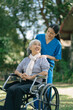 © NINENII - Smiling physiotherapist taking care of the happy senior patient in wheelchair, outdoor.