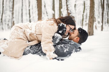 Portrait of a romantic couple lay in snow in winter forest