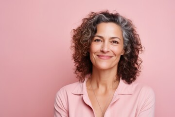 Wall Mural - Portrait of smiling mature woman looking at camera over pink background.