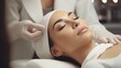 © Phoophinyo - A Beauty expert massaging young woman's face Close up of beautiful Asian woman's head in white hat and doctor's hands in gloves lying on treatment bed.