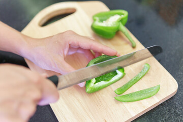 Canvas Print - Woman hands cutting fresh green bell pepper in a kitchen