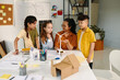 © DragonImages - School kids gathered around table with model of small wind turbine