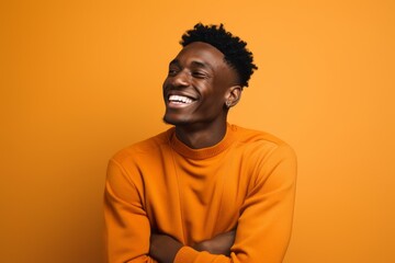 Wall Mural - happy african american man laughing and looking up on orange background