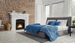 A bed adorned with blue pillows and a coverlet positioned near a fireplace takes center stage in the loft-style interior design of a modern bedroom. Exposed brick walls add character, and a white door