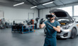 © velimir - male auto mechanic repairs a car in a car service garage wearing VR glasses, augmented reality in the industry.