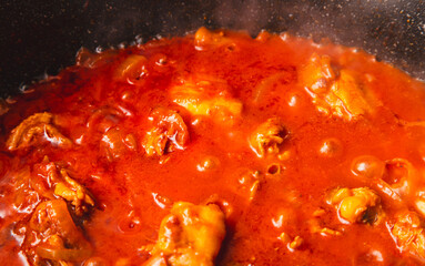 Canvas Print - Chicken meat is stewed in tomato in a frying pan