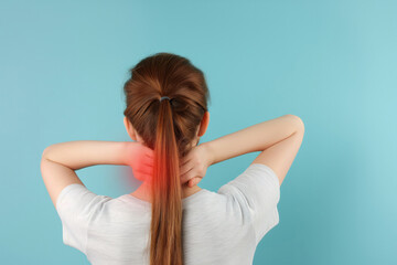 Wall Mural - Girl massaging her back and neck, cervical pain, back portrait on blue background with space for your text