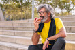 © Raul Mellado - senior sports man rests eating an apple after a hard workout, concept of healthy and active lifestyle in the middle age, copy space for text