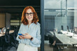 © Jacob Lund - Young businesswoman using her smartphone in an office, happy employee in tech company