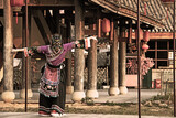 Fototapeta Młodzieżowe - a young girl in a Chinese national dress, wearing a dragon mask, against the background of national buildings of houses, hanging red fanariks