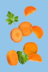 Wall Mural - Fresh carrot slices and green parsley falling on light blue background