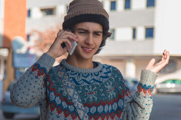 Wall Mural - young urban man wearing winter clothes on the street talking on mobile phone