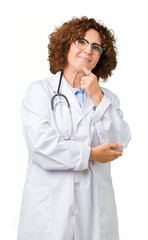 Canvas Print - Middle ager senior doctor woman over isolated background looking confident at the camera with smile with crossed arms and hand raised on chin. Thinking positive.