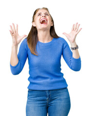 Poster - Beautiful middle age mature woman wearing winter sweater over isolated background crazy and mad shouting and yelling with aggressive expression and arms raised. Frustration concept.