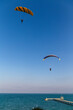 Paraglider flying over the sea coast in blue sky background