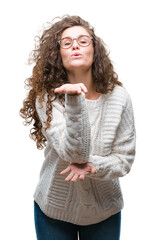 Sticker - Beautiful brunette curly hair young girl wearing winter sweater over isolated background looking at the camera blowing a kiss with hand on air being lovely and sexy. Love expression.