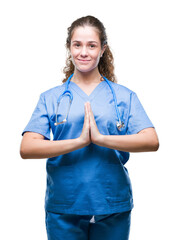 Sticker - Young brunette doctor girl wearing nurse or surgeon uniform over isolated background praying with hands together asking for forgiveness smiling confident.