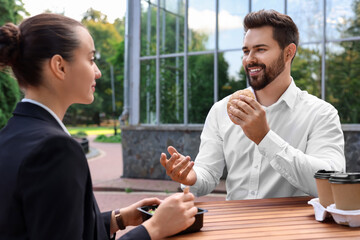 Canvas Print - Business lunch. Happy colleagues spending time together at wooden table during break outdoors