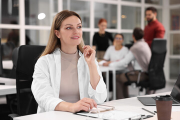 Canvas Print - Team of employees working together in office. Happy woman at table indoors