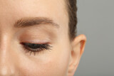 Fototapeta Panele - Woman with long eyelashes after mascara applying against grey background, closeup