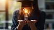 © Keitma - College student girl showing a light bulb for education, E-learning graduate certificate and business concept, woman with graduation regalia hat for creative thinking idea and human development