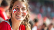 © Keitma - Happy Swiss woman supporter with face painted in Switzerland flag colors, white and red, Swiss fan at a sports event such as football or rugby match, blurry stadium background, copy space