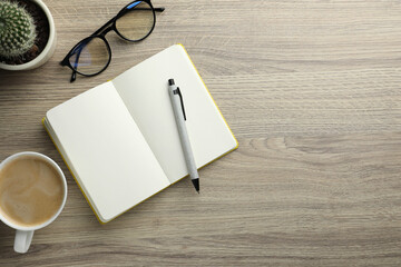 Wall Mural - Open notebook, pen, glasses and cup of coffee on wooden table, flat lay. Space for text