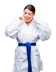 Poster - Young beautiful woman wearing karate kimono uniform over isolated background covering ears with fingers with annoyed expression for the noise of loud music. Deaf concept.