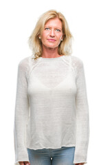 Wall Mural - Middle age blonde woman wearing winter sweater isolated background with serious expression on face. Simple and natural looking at the camera.