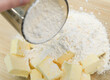 Mąka dodawana do składników na kruche ciasto w szklanej misce 