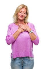 Sticker - Middle age blonde woman over isolated background smiling with hands on chest with closed eyes and grateful gesture on face. Health concept.