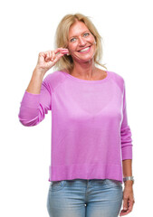 Canvas Print - Middle age blonde woman eatin pink macaron biscuit over isolated background with a happy face standing and smiling with a confident smile showing teeth