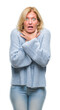 Middle age blonde woman wearing winter sweater over isolated background shouting and suffocate because painful strangle. Health problem. Asphyxiate and suicide concept.