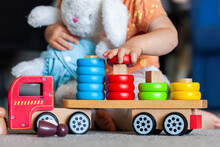 Toddler Placing Coloured Shape On Correct Peg Of Wooden Toy Truck