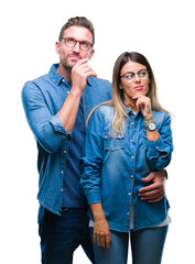 Sticker - Young couple in love wearing glasses over isolated background with hand on chin thinking about question, pensive expression. Smiling with thoughtful face. Doubt concept.