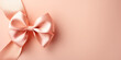 Peach pastel ribbon tied in a neat bow on soft pink background. Minimalistic backdrop. Holiday concept. Design for For Birthday, Valentine's Day and Mother’s day cards. Banner with copy space 