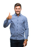 Fototapeta Natura - Young handsome man over isolated background doing happy thumbs up gesture with hand. Approving expression looking at the camera with showing success.